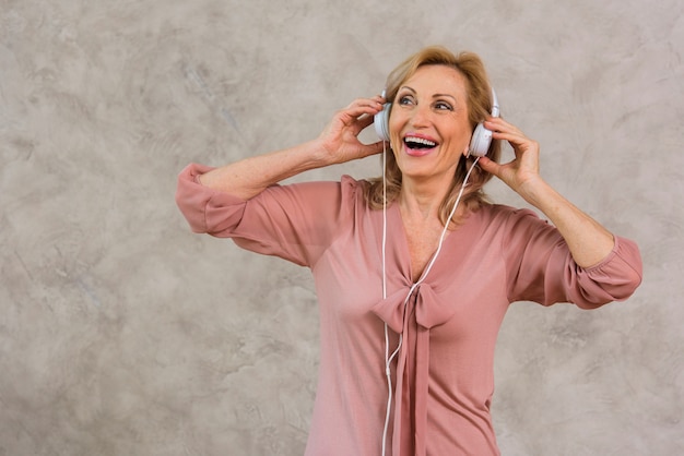 Smiley blond dama słuchanie muzyki na zestawie słuchawkowym