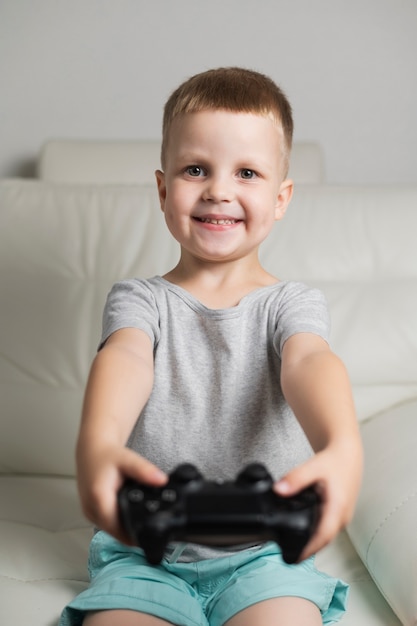 Smiley boy patrząc na kamery z joystickiem