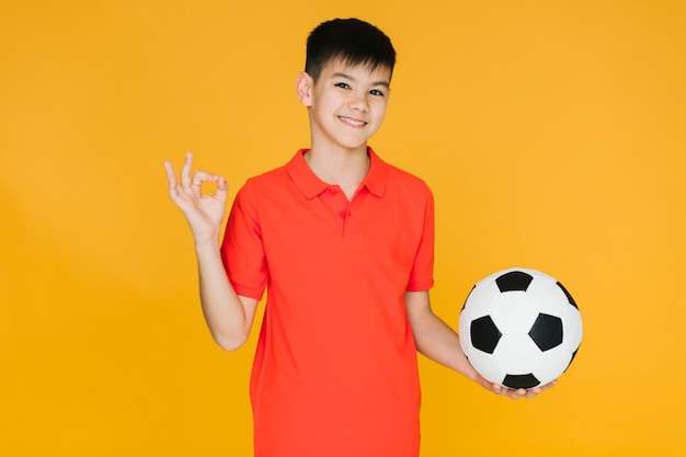 Smiley chłopiec trzyma futbolową piłkę
