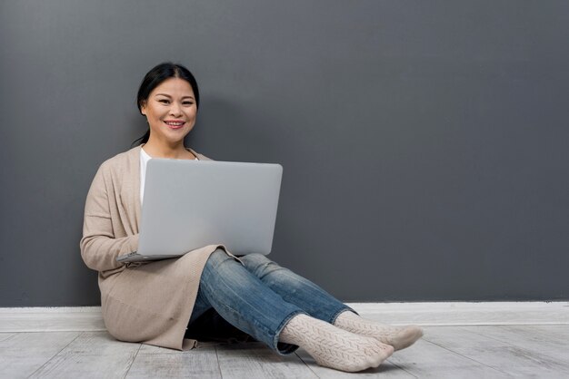 Smiley kobieta na podłoga z laptopem