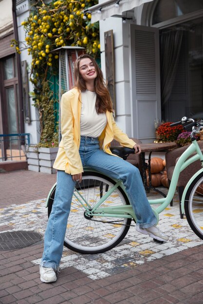 Smiley kobieta pozuje na swoim rowerze w mieście
