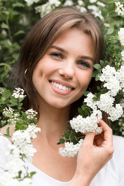 Smiley kobieta pozuje w kwiatach