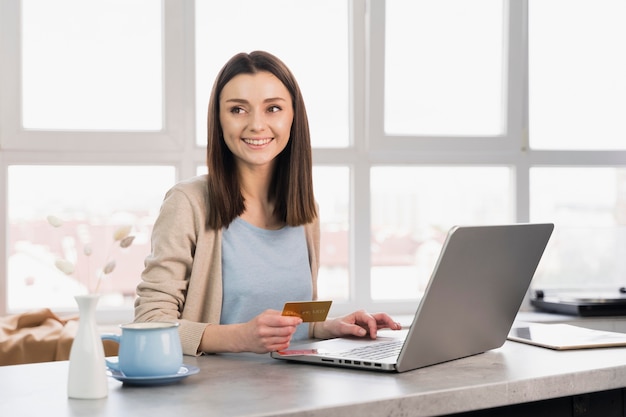Smiley kobieta przy biurkiem pracuje na laptopie