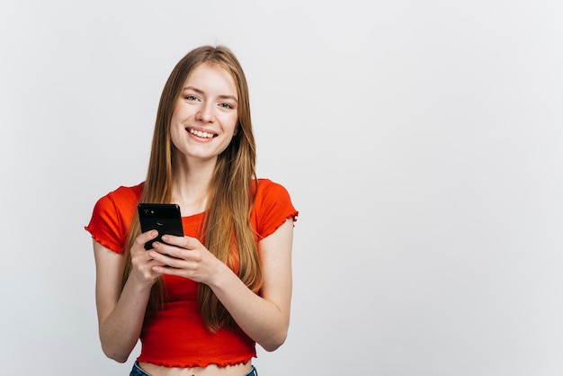 Smiley kobieta sprawdza jej telefon z kopii przestrzenią
