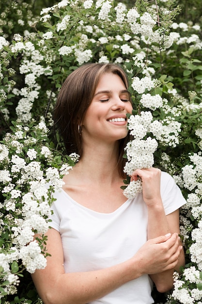 Smiley kobieta w naturze wącha kwiaty