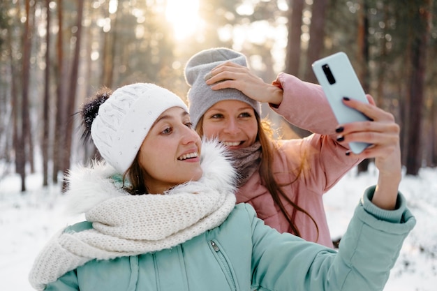 Bezpłatne zdjęcie smiley przyjaciele robienia selfie na zewnątrz w zimie