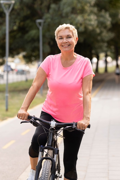 Smiley starszy kobieta jedzie na rowerze na zewnątrz