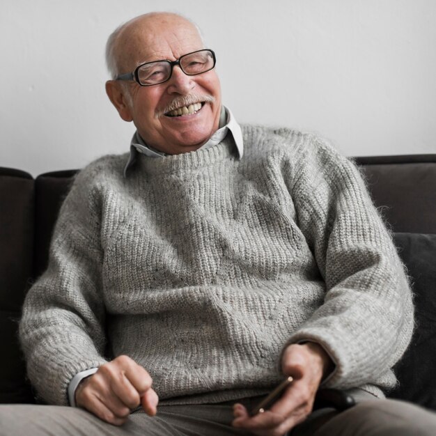 Smiley starszy mężczyzna w domu opieki, trzymając smartfon