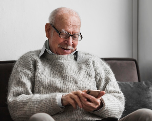 Smiley starzec za pomocą smartfona w domu opieki
