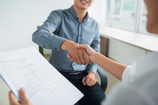 Bezpłatne zdjęcie smiling azjatycki biznesmen wstrząsając ręce partnerów