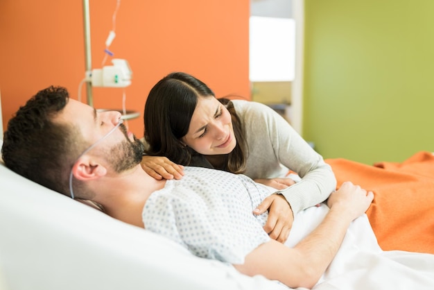 Smutna kobieta płacze, obejmując chorego mężczyznę podczas wizyty w szpitalu