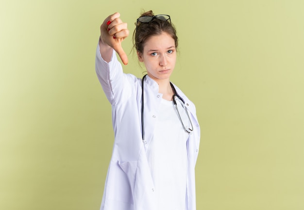 Smutna młoda kobieta w mundurze lekarza ze stetoskopem w dół