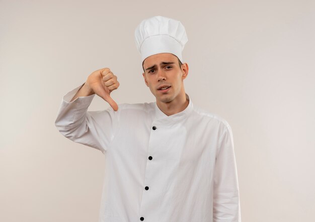Smutny młody kucharz mężczyzna ubrany w mundur szefa kuchni kciuk w dół z miejsca na kopię