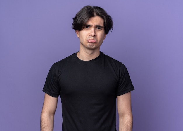 Smutny, młody przystojny facet na sobie czarną koszulkę na białym tle na fioletowej ścianie