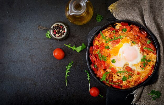 Śniadanie. Jajka sadzone z warzywami. shakshuka na patelni na czarnym w tureckim stylu.