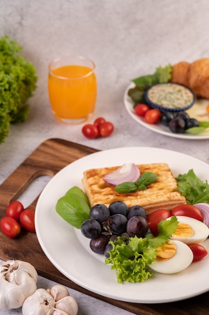 Śniadanie składa się z chleba, gotowanych jajek, sosu sałatkowego z czarnych winogron, pomidorów i pokrojonej w plasterki cebuli.