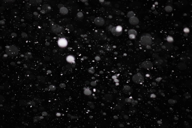 Śnieg na czarnym tle. płatki śniegu na nakładkę. śnieg w tle.
