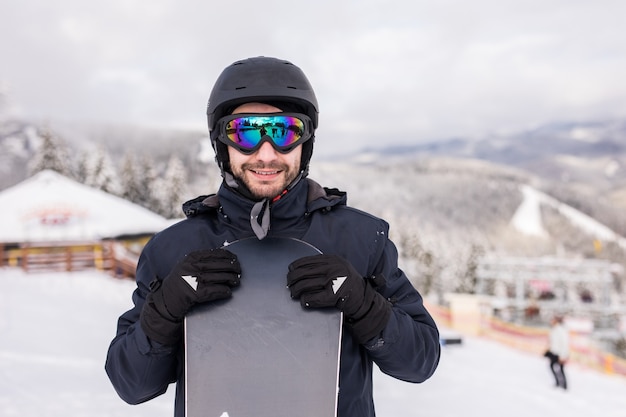 Snowboardzista człowiek stoi ze snowboardem. Portret zbliżenie.