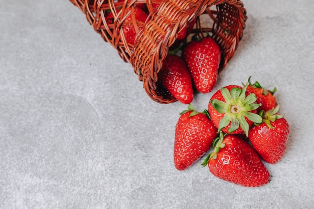 Soczyste truskawki wylewały się chaotycznie na betonową lekką ścianę. pyszne owoce w sezonie letnim. produkty naturalne i zasoby naturalne.