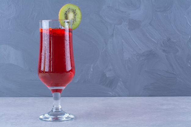 Bezpłatne zdjęcie sok wiśniowy w szklance z plasterkiem kiwi na marmurowym stole.