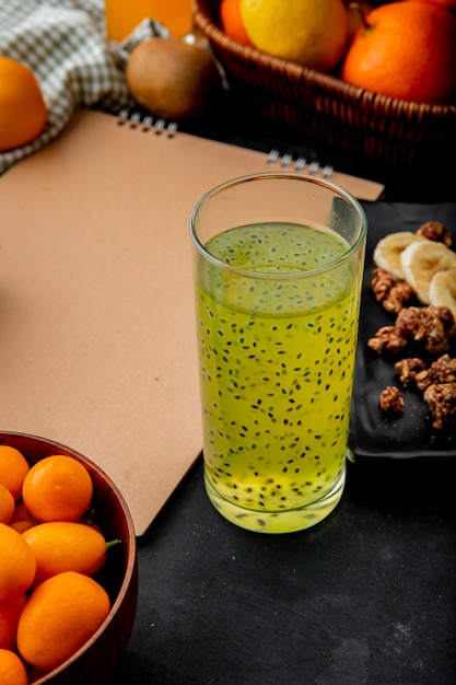 Bezpłatne zdjęcie sok z kiwi z kumkwatami i innymi owocami na czarnej powierzchni z miejsca kopiowania