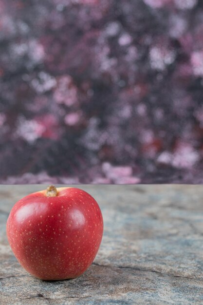 Songle czerwone jabłko na białym tle na betonie.
