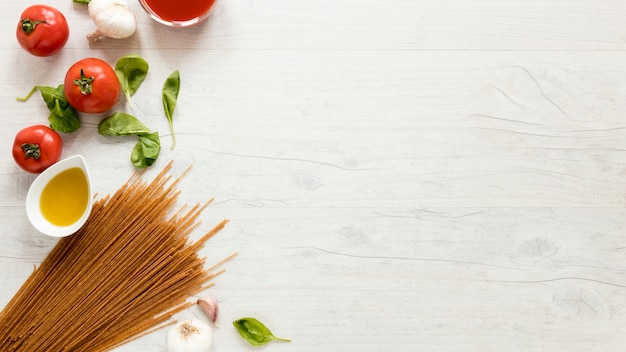 Bezpłatne zdjęcie spaghetti makaron i świezi składniki nad białym stołem