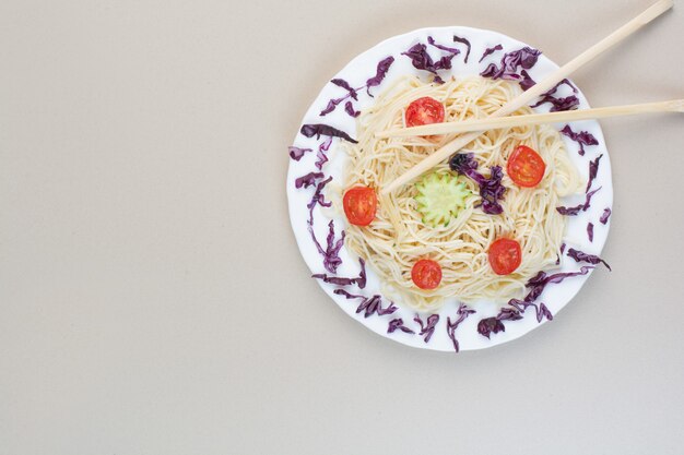 Spaghetti z kapustą i plasterkami pomidora na białym talerzu