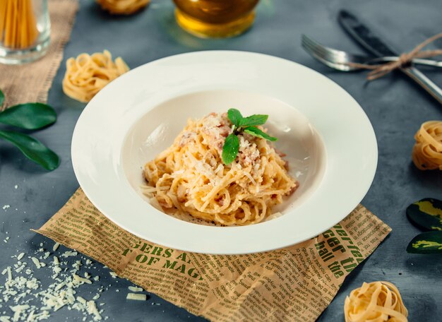 Spaghetti z posiekanym parmezanem i zielonymi liśćmi mięty.