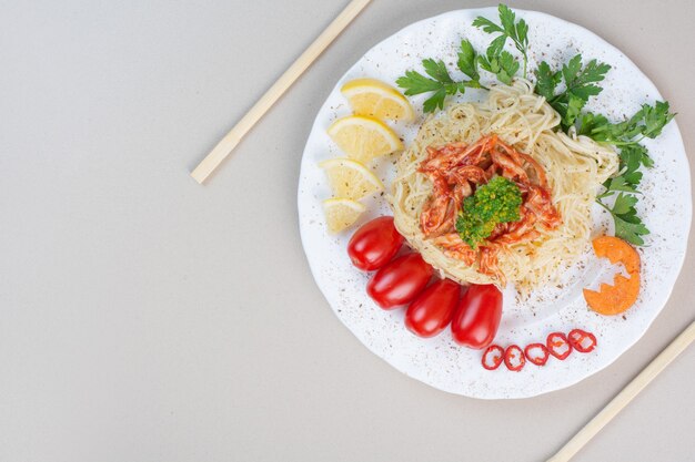 Spaghetti z siekanym kurczakiem i warzywami na białym talerzu