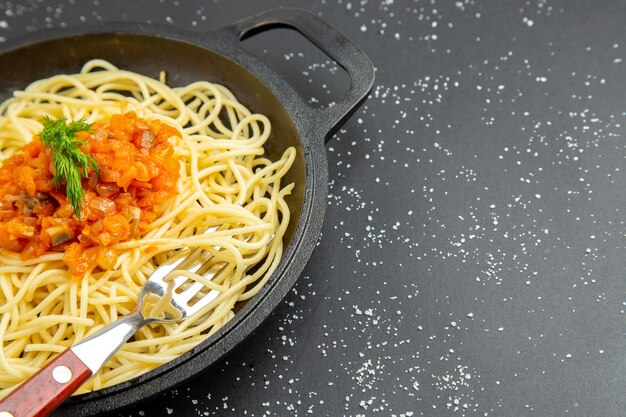 Spaghetti z sosem na patelni na czarnym stole