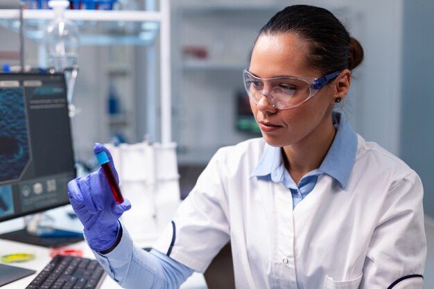 Specjalista chemik patrzący na medycznego vacutainera z mikrobiologiczną ekspertyzą analizy krwi