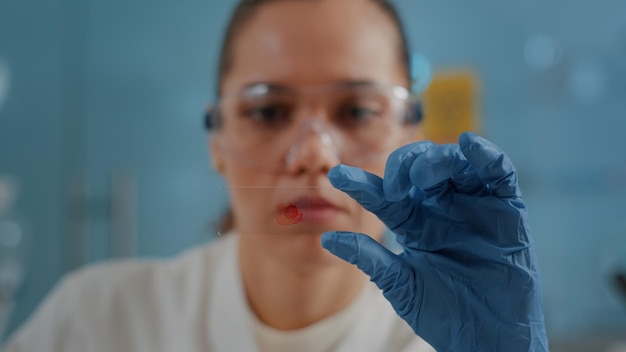 Bezpłatne zdjęcie specjalista chemik trzymający szklaną tacę z próbką krwi do analizy cząsteczki i przeprowadzenia badań w laboratorium. naukowiec badający dna pod kątem rozwoju biologii w laboratorium. ścieśniać