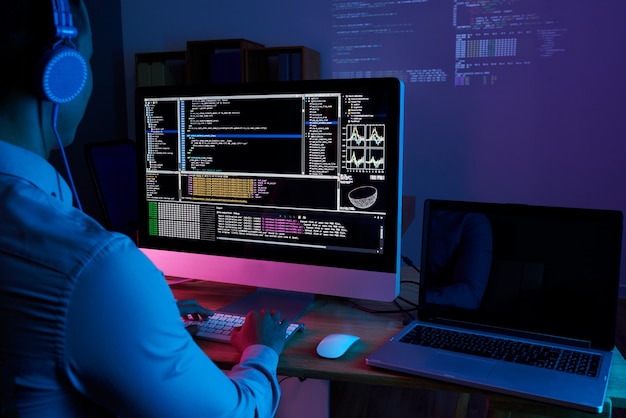 Specjalista IT sprawdza kod przy komputerze w ciemnym biurze w nocy