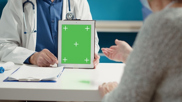 Bezpłatne zdjęcie specjalista medyczny posiadający cyfrowy tablet z greenscreenem na wizytę konsultacyjną w gabinecie. pusty szablon klucza chrominancji z na białym tle makieta i miejsce. ścieśniać.