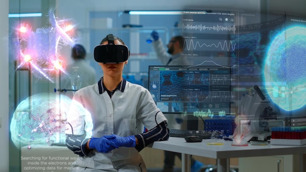 Specjalista naukowy w laboratorium badawczym noszący okulary VR używający wysokiej technologii sprzętu i przewodów czujników do badań medycznych.