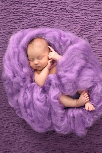 Śpiąca noworodka na różowym wełnianym tle zbliżeniu