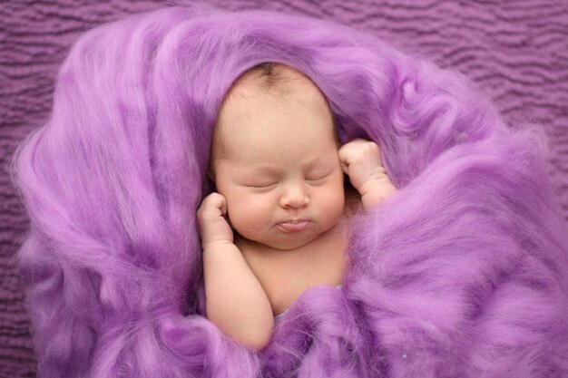 Śpiąca noworodka na różowym wełnianym tle zbliżeniu