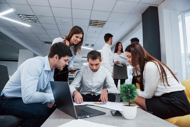 Spójrz na ten wykres. Grupa młodych freelancerów w biurze rozmawia i uśmiecha się