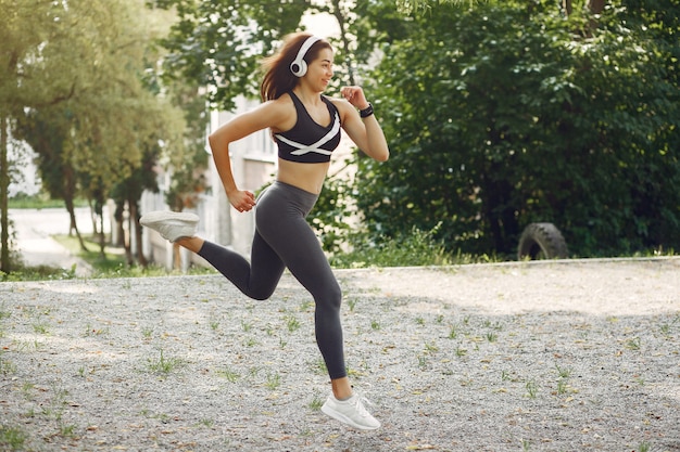 Sport dziewczyna szkolenia ze słuchawkami w parku lato