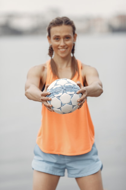 Sportowa Dziewczyna Nad Wodą. Kobieta W Letnim Parku. Pani W Pomarańczowym Stroju Sportowym.