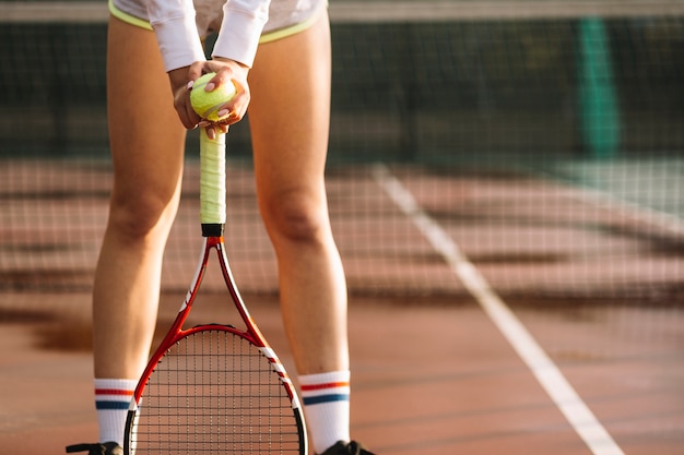 Sportowa kobieta spoczywa na rakiecie tenisowym
