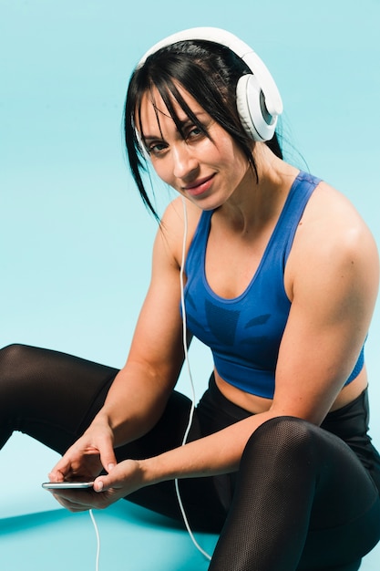 Sportowa kobieta w gym stroju pozuje z hełmofonami