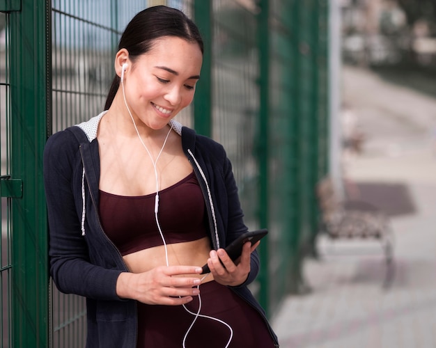 Bezpłatne zdjęcie sportowa młoda kobieta wyszukuje telefon komórkowego