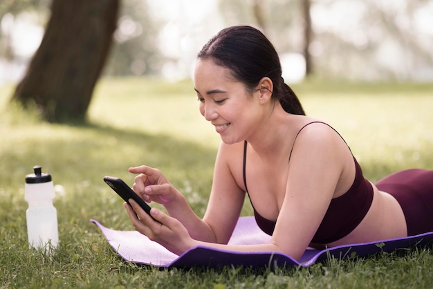 Sportowa młoda kobieta wyszukuje telefon komórkowego