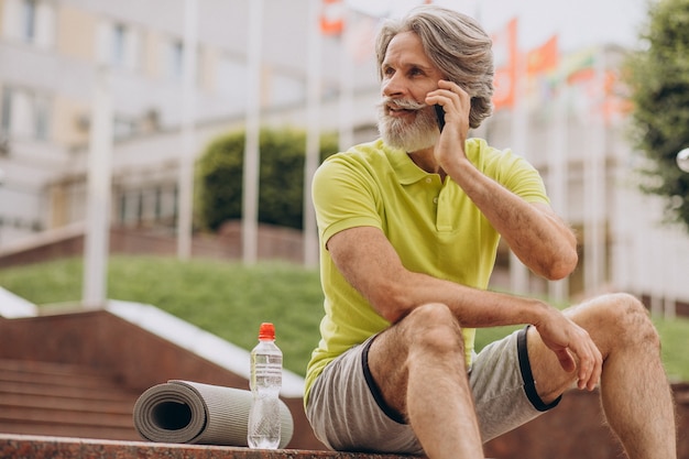 Sportowca w średnim wieku siedzi na schodach przy użyciu telefonu