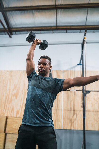 Sportowiec Crossfit robi ćwiczenia z hantlami.