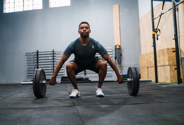 Sportowiec crossfit robi ćwiczenia ze sztangą.