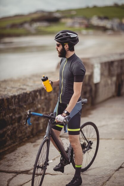 Sportowiec orzeźwiający się z butelki podczas jazdy na rowerze