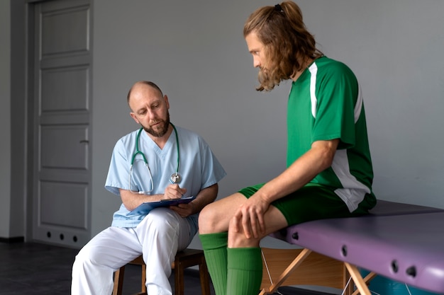 Bezpłatne zdjęcie sportowiec rozmawiający z fizjoterapeutą widok z boku